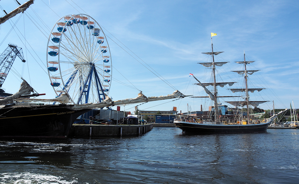 Riesenrad und Segelschiffe, der Kontrast im Rostocker Stadthafen.